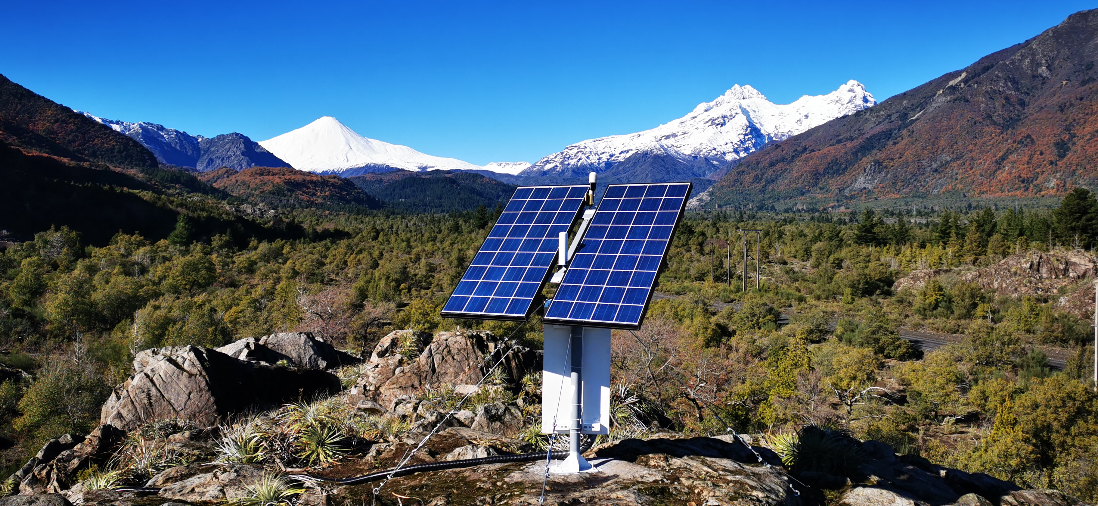 Estación solar con volcán nevado en los Andes